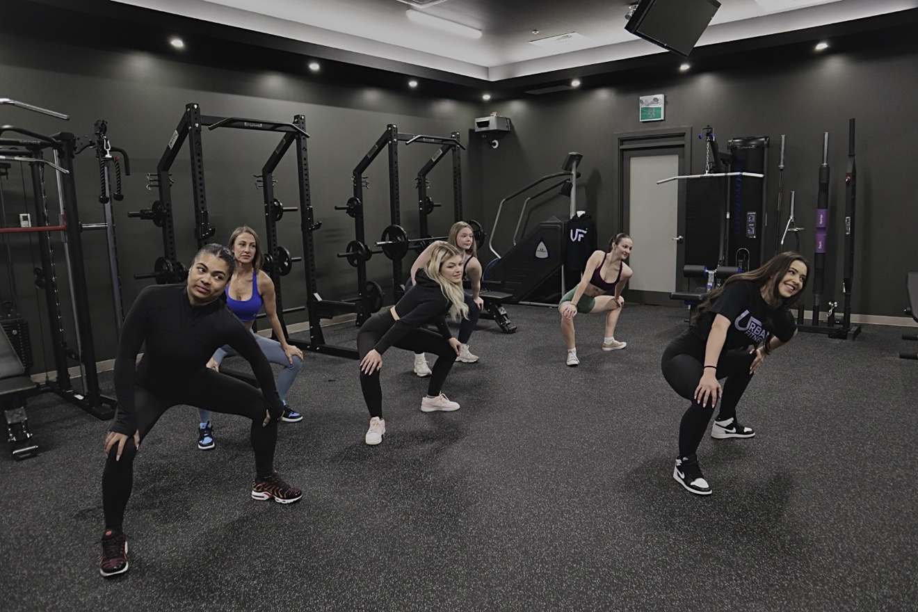 A coach leading clients through lateral lunges in a small-group session