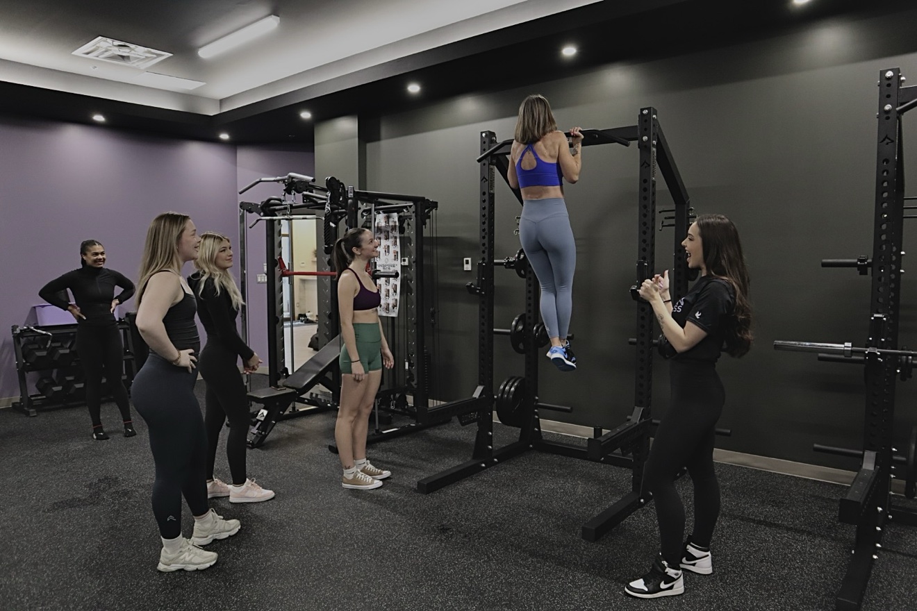 A coach guiding a small group while a client performs a pull-up